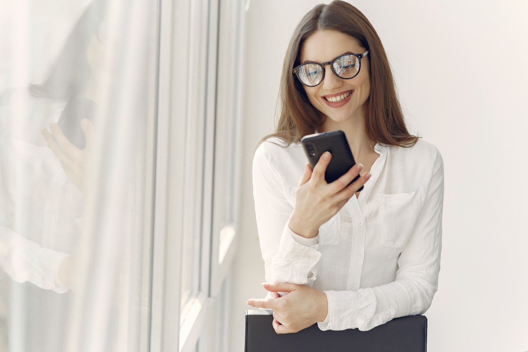 Smiling woman using smartphone in office